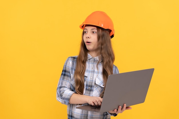 コンピューターの驚きを使用してヘルメットと市松模様のシャツで驚いた10代の少女