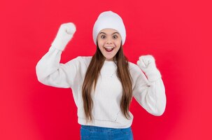写真 surprised teen girl in warm winter knitwear sweater and mittens in studio teen winter girl