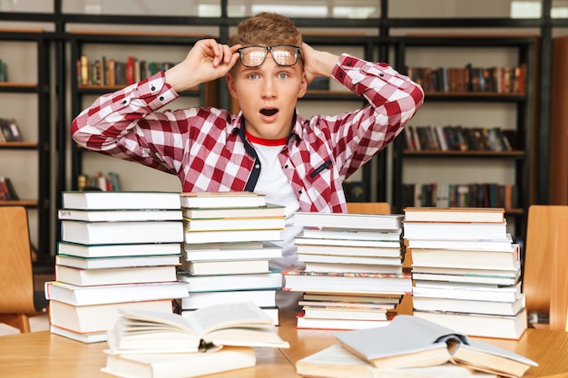 Ragazzo adolescente sorpreso seduto al tavolo della biblioteca