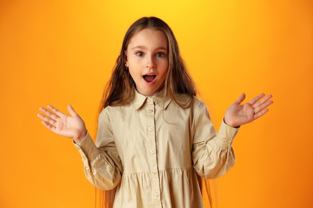 Photo surprised teenage girl over yellow background in studio