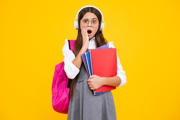 Ragazza adolescente sorpresa ragazza studentessa adolescente scolara con le cuffie e lo zaino della borsa della scuola