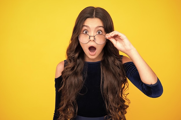 Photo surprised teenager girl shocked amazed face portrait of teenager child in glasses kid at eye sight test girl holding eyeglasses and looking at camera eyesight measurement for school children