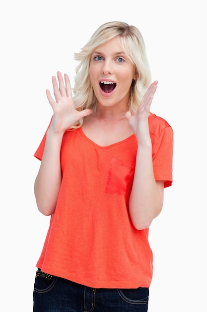 Surprised teenager standing upright with her arms next to her head