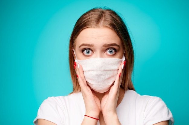 Surprised woman in aseptic mask in isolated blue