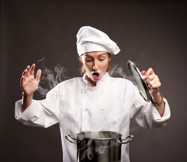 Photo surprised woman chef holding a lid