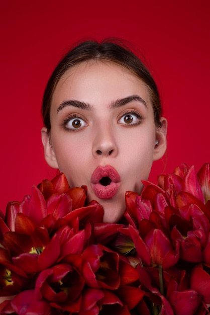 Surprised woman face with flowers beauty girl with tulip beautiful sensual woman hold tulips bouquet