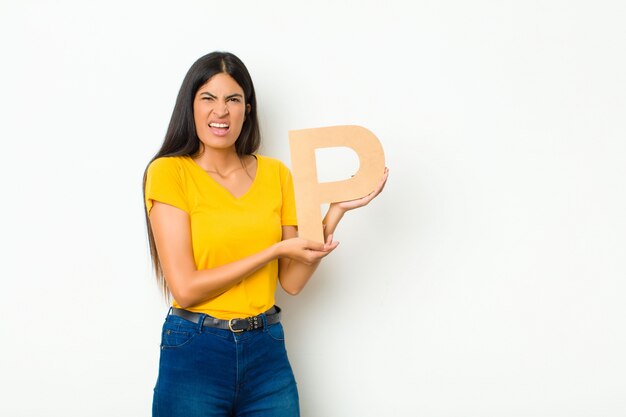 Surprised woman holding the letter P of the alphabet to form a word or a sentence