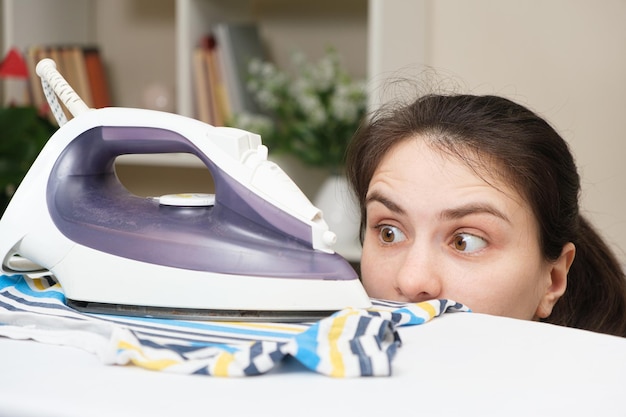 A surprised woman looks at the iron on the ironing board