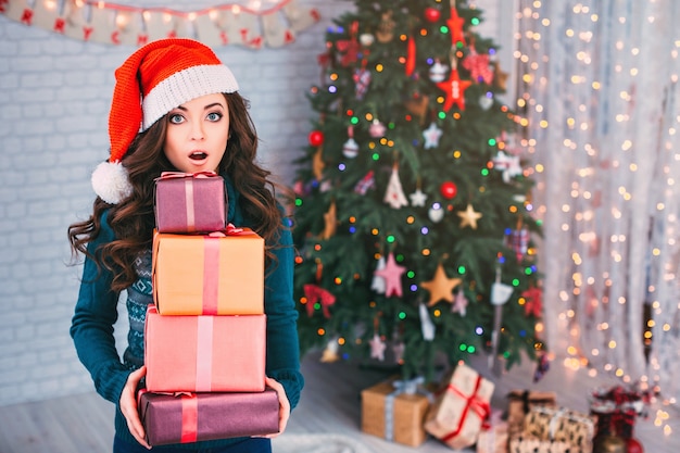 Surprised woman with gifts and Christmas tree. Christmas sale.