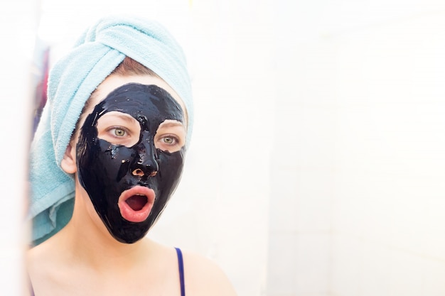 Foto donna sorpresa con la bocca aperta con maschera cosmetica sul viso