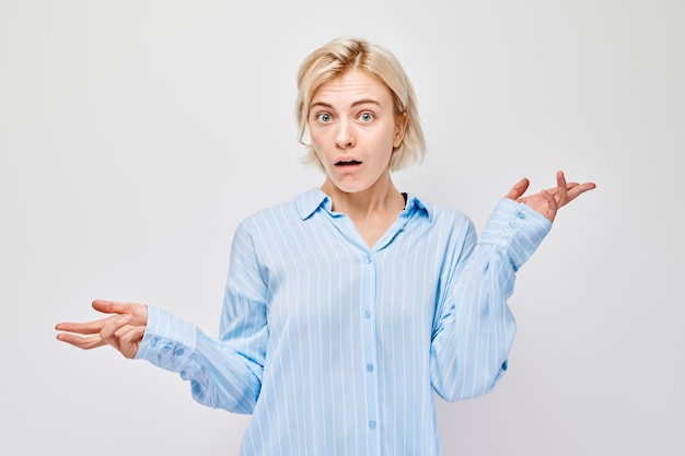 Surprised woman with raised hands expressing confusion on a white background