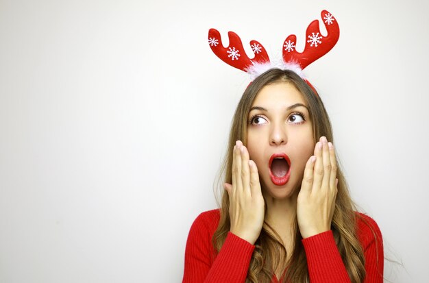 Foto donna sorpresa con le corna della renna che osserva al lato nelle vacanze invernali di natale