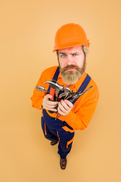 Surprised worker holds repair tools building builder in construction helmet repairment tools