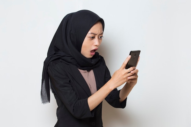 Surprised young asia muslim woman using mobile phone on white background