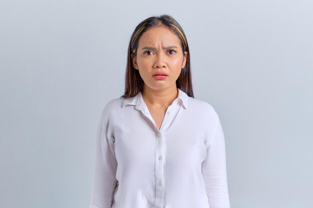 Surprised young Asian woman looking at camera with open mouth isolated over white background