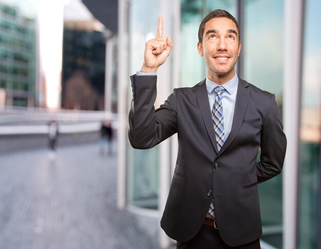 Surprised young businessman pointing up