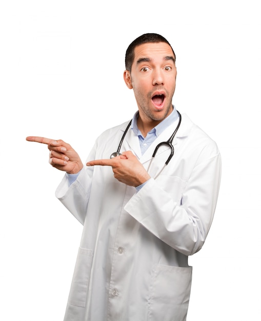 Surprised young doctor pointing