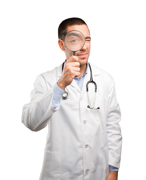 Surprised young doctor using a magnifying glass