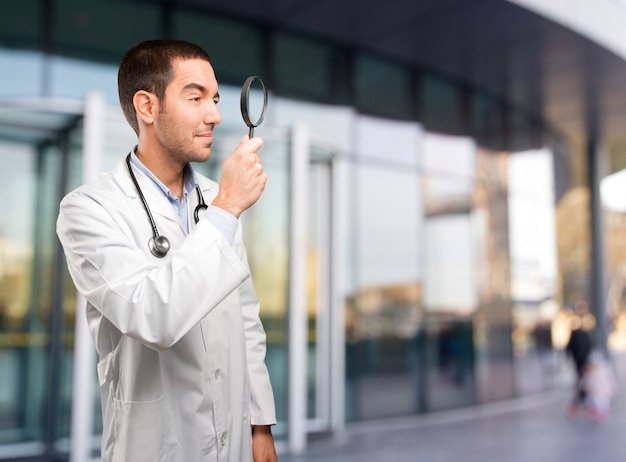 Surprised young doctor using a magnifying glass