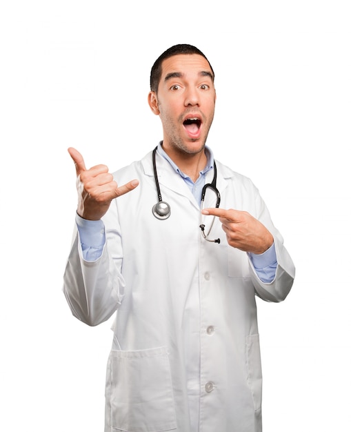 Surprised young doctor with call gesture