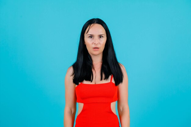 Surprised young girl is looking at camera on blue background