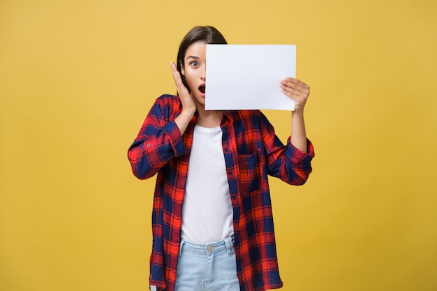 Ragazza sorpresa in camicia rossa con carta bianca cartello nelle mani