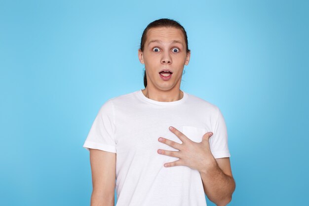 Surprised young handsome guy isolated on blue background. Human emotions, facial expressions