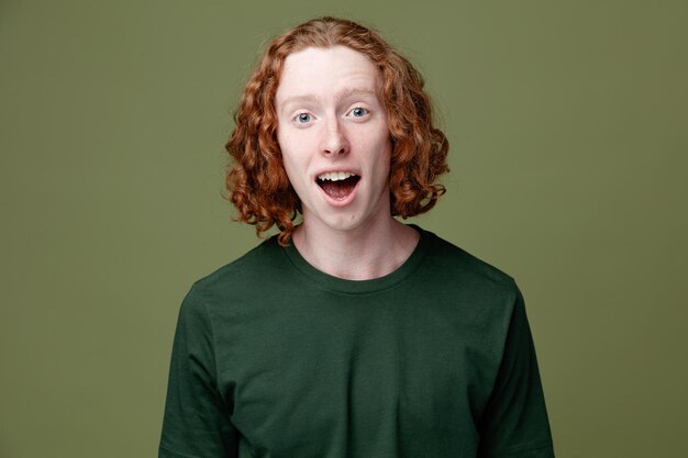 Surprised young handsome guy wearing green t shirt isolated on green background