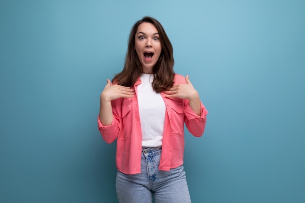 Surprised young lady in shirt and jeans with open mouth on studio isolated background