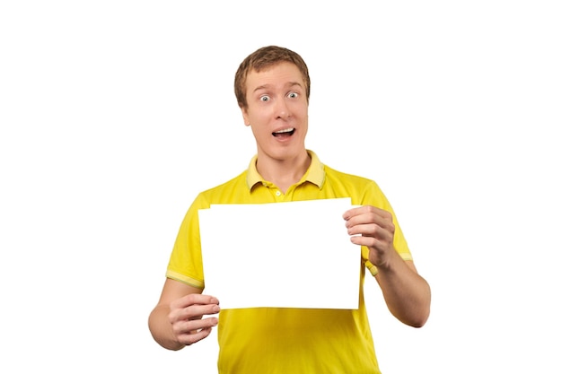 Удивленный молодой человек держит макет листа бумаги на белом фоне