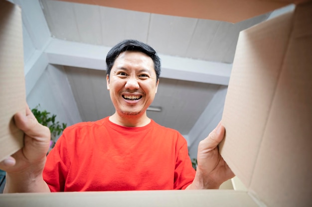 Surprised young man is opening a large cardboard box