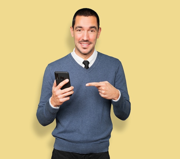 Surprised young man pointing and using his mobile phone