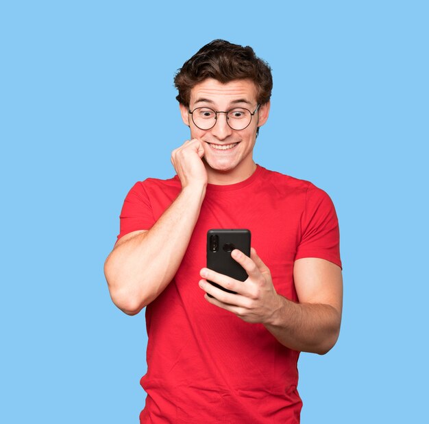 Surprised young man using his mobile phone