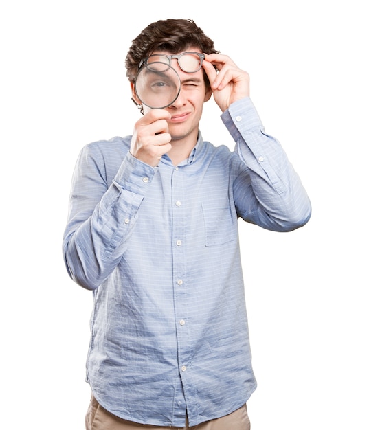 Surprised young man using a magnifying glass