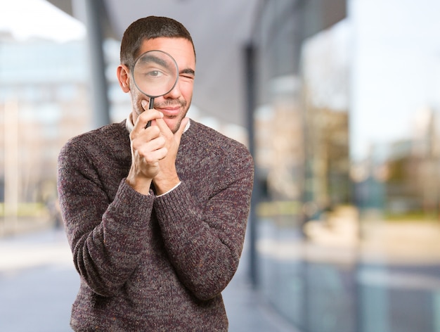 Surprised young man using a magnifying glass