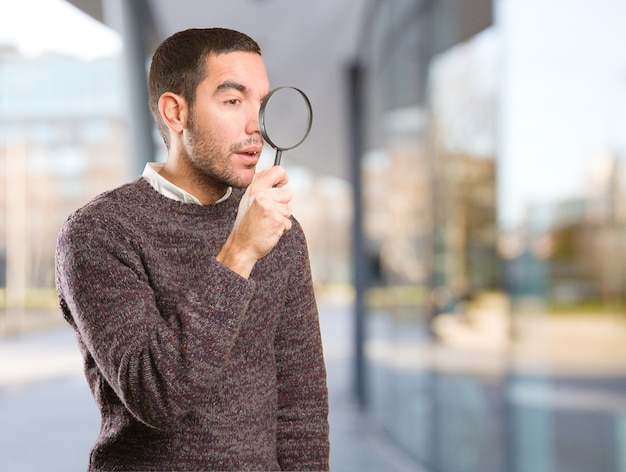 Surprised young man using a magnifying glass