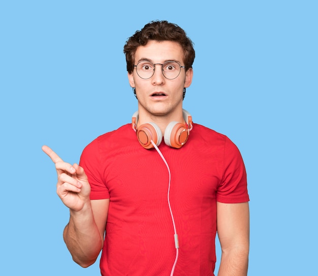 Surprised young man using a smartphone and pointing with his finger