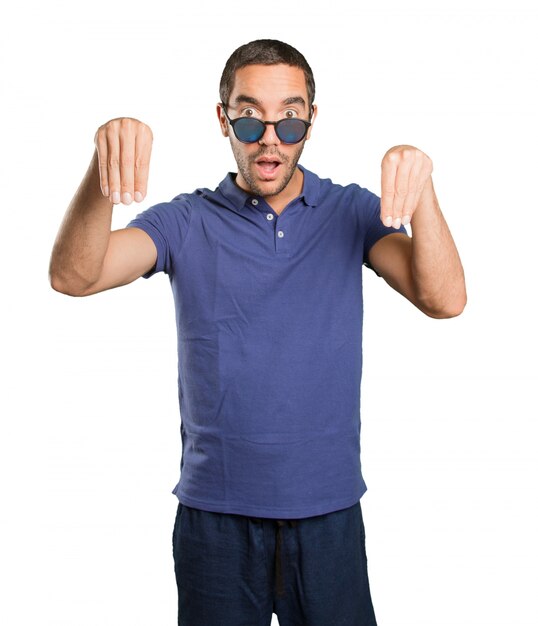 Surprised young man with pick up gesture on white background