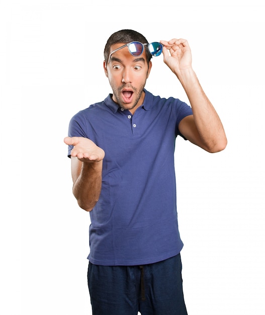 Surprised young man with pick up gesture on white background