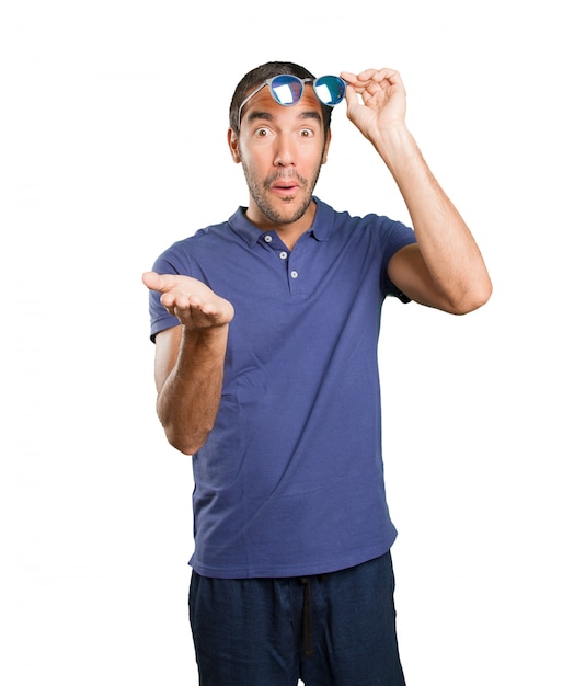 Surprised young man with pick up gesture on white background