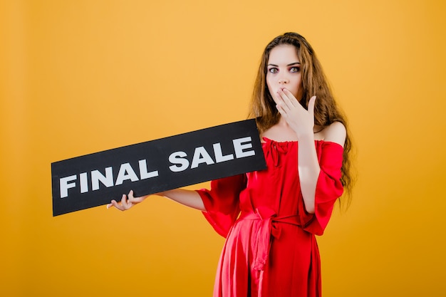 Surprised young woman has final sale sign isolated over yellow