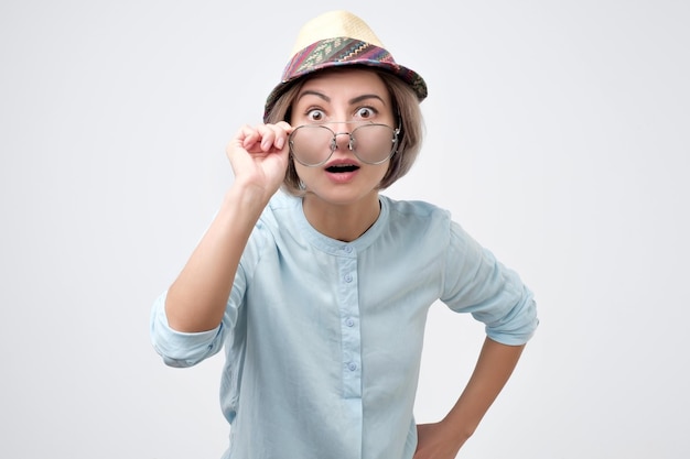 Surprised young woman in hat and glasses with open mouth