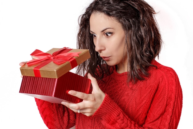 Удивленная молодая женщина, открывающая подарочную коробку крупным планом