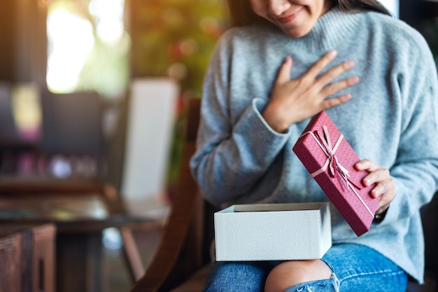 Surprised young woman opening a gift box