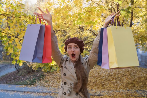 Surprised young woman with shopping bags in hands. Fall discounts.