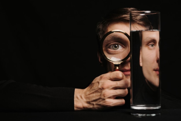 Фото Сюрреалистический портрет мужчины через увеличительное стекло и емкость с водой