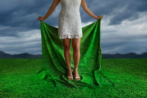 Surrealistisch beeld van een vrouw die het gras met haar handen opheft
