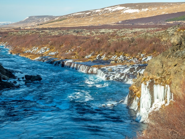 Окружающий вид вокруг водопада Храунфоссар необычная красивая природная достопримечательность Исландии