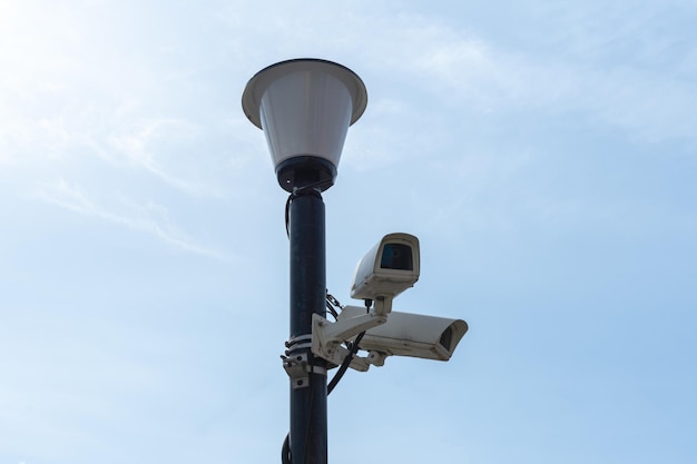 Камеры наблюдения, установленные на фонарном столбе на фоне голубого неба, камеры видеонаблюдения Безопасность в городе