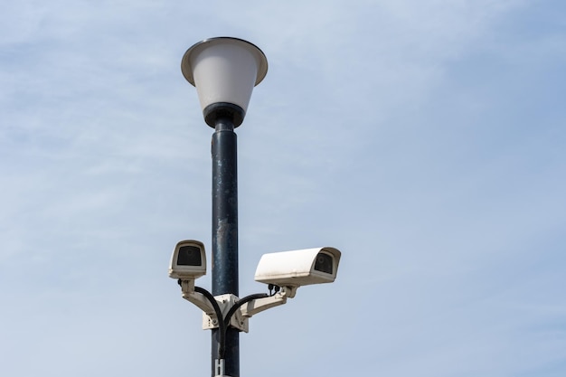 Surveillance cameras mounted on a lamp post against a blue sky security cctv camera Security in the city